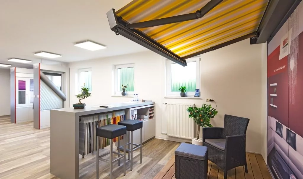 Getreu der Produktpalette des Jalousie-Center Katsch "beschattet" am Eingang zur Ausstellung eine gelb-weiße Markise eine Sitzgelegenheit.