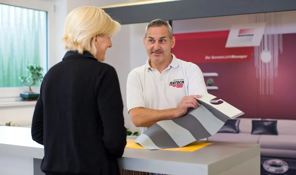 Eine Kundin wird zu verschiedenen Stoffen und Mustern beraten, die beim Jalousie-Center Katsch erhältlich sind.
