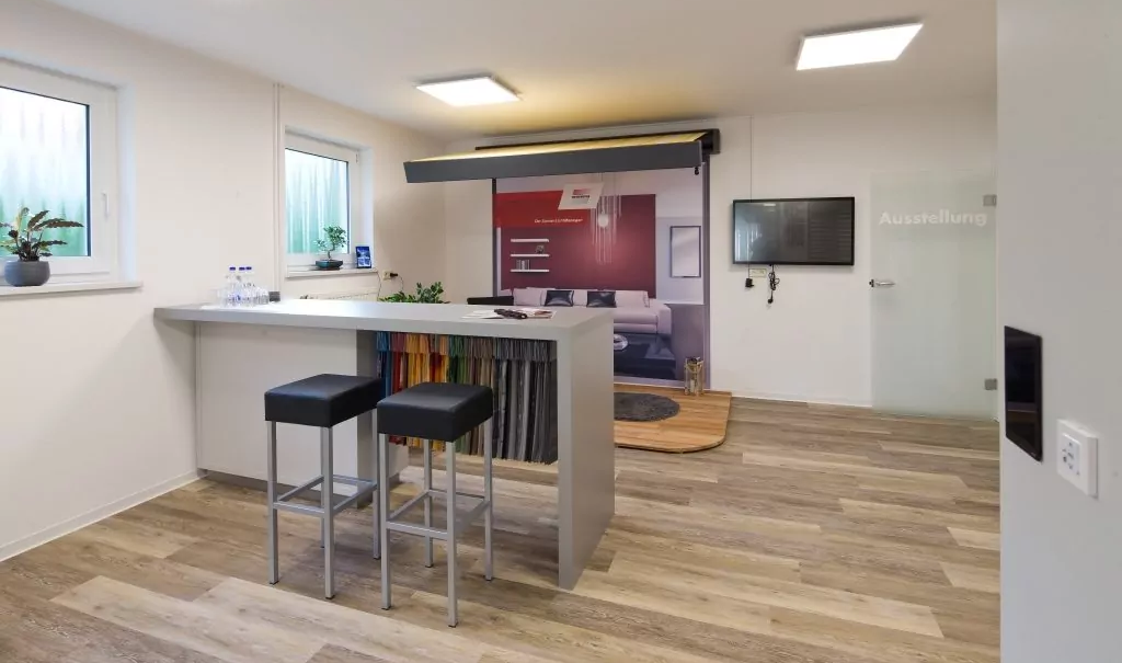 Am Eingangsbereich der Ausstellung befinden sich ein Tresen mit Stoffmustern und Sitzgelegenheiten, sowie eine erste ausgestellte Markise.