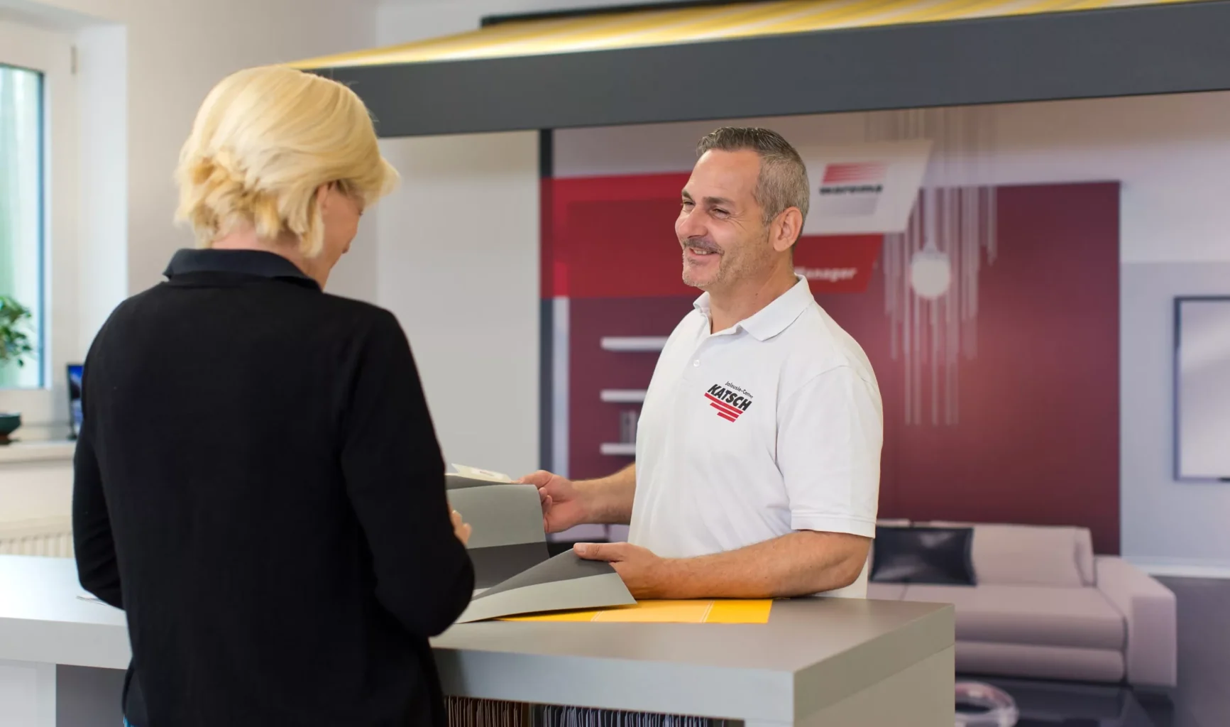 Ein Mitarbeiter berät eine Kundin zu Farben und Stoffen in der Ausstellung des Jalousie-Center Katsch.