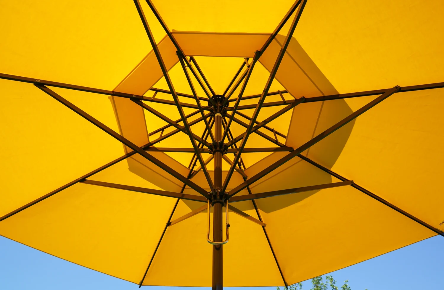 Gelber Sonnenschirm von unten mit blauen Himmel im Hintergrund